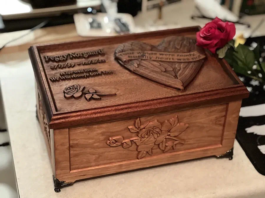 A hardwood keepsake box with a three-dimensional relief carved lid of roses and a heart.