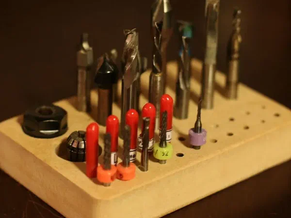 A rounded wooden block drilled with holes to store CNC router bits.