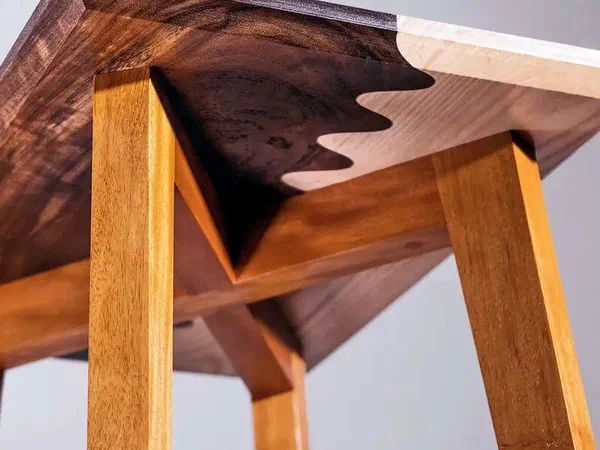 A side table with a two-tone wooden top joined by a wavy seam.